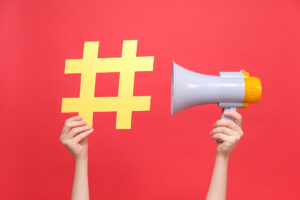 Female hands holding yellow hashtag sign and megaphone - encouraging you to look at hashtag strategies on Instagram