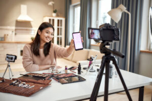 Female blogger filming herself, advertising an app on her smartphone
