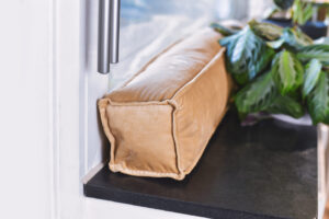Draft excluder lying on windowsill to keep out cold air and save energy for heating in room