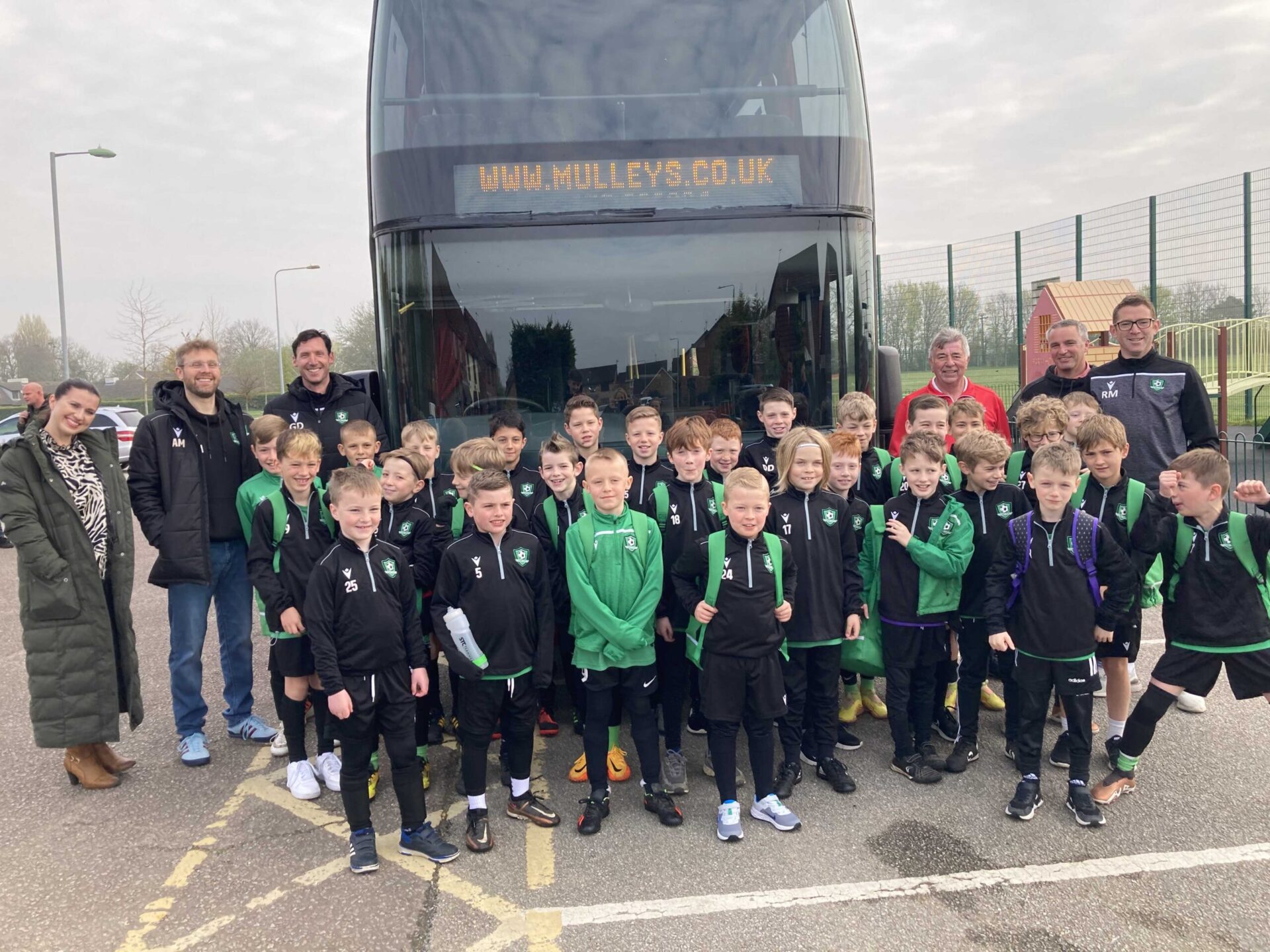 Elmswell U9 and U10 football teams standing in front of the bus.