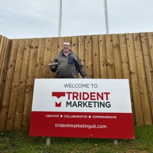 Tony Harris in front of the Trident Marketing sign.