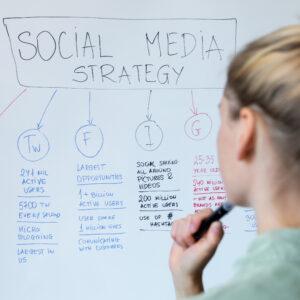 A female digital marketer with a whiteboard and pen, working out a social media strategy