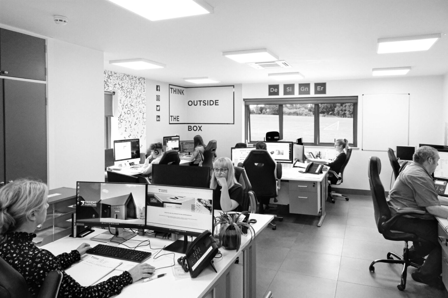 Black and white photograph of staff inside the Trident Marketing office