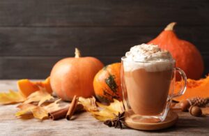 A pumpkin spice latte surrounded by pumpkins and autumn leaves - a perfect example of the power of seasonal marketing